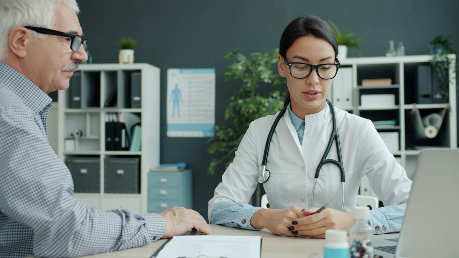 Une médecin en consultation avec un patient âgé, dans un cabinet de ville.