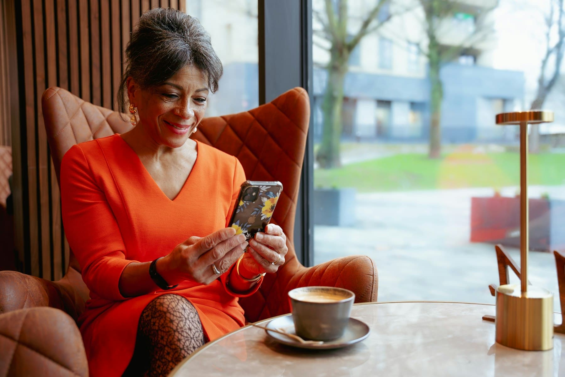 Une patiente attend dans un fauteuil, son téléphone en main, un café sur la table.